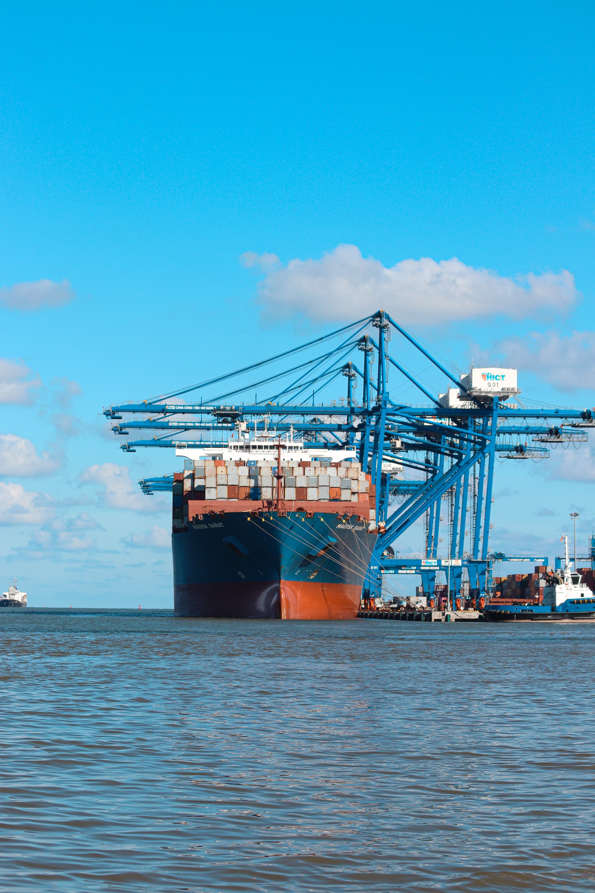 Large container ship docked at Hai Phong International Container Terminal with cargo cranes and stacked shipping containers