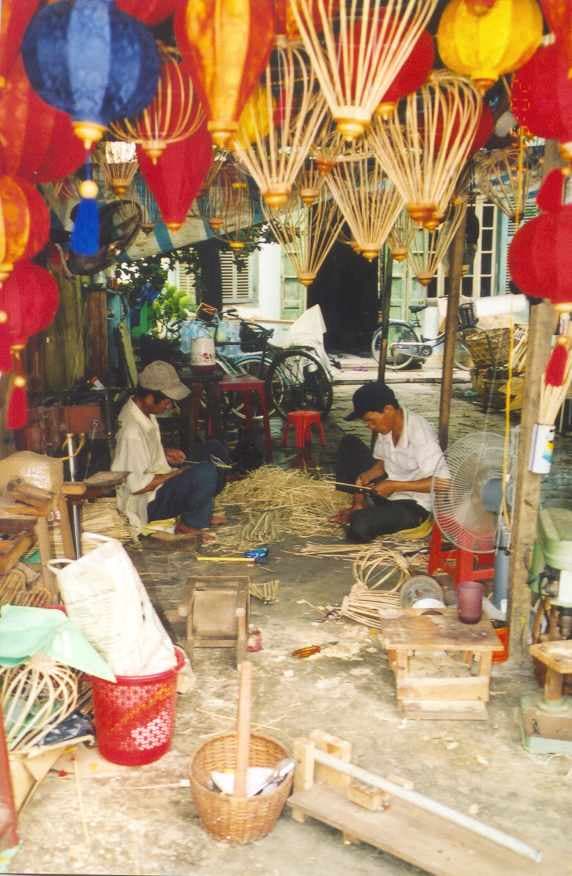 Colorful silk lanterns hanging in a traditional Hoi An lantern shop, with ornate designs and warm lighting reflecting on the lantern surfaces.