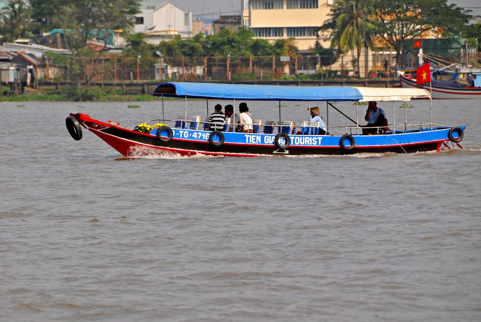 Tourist boat on the Mekong River with verdant banks and traditional waterway landscape typical of Vietnam's Mekong Delta