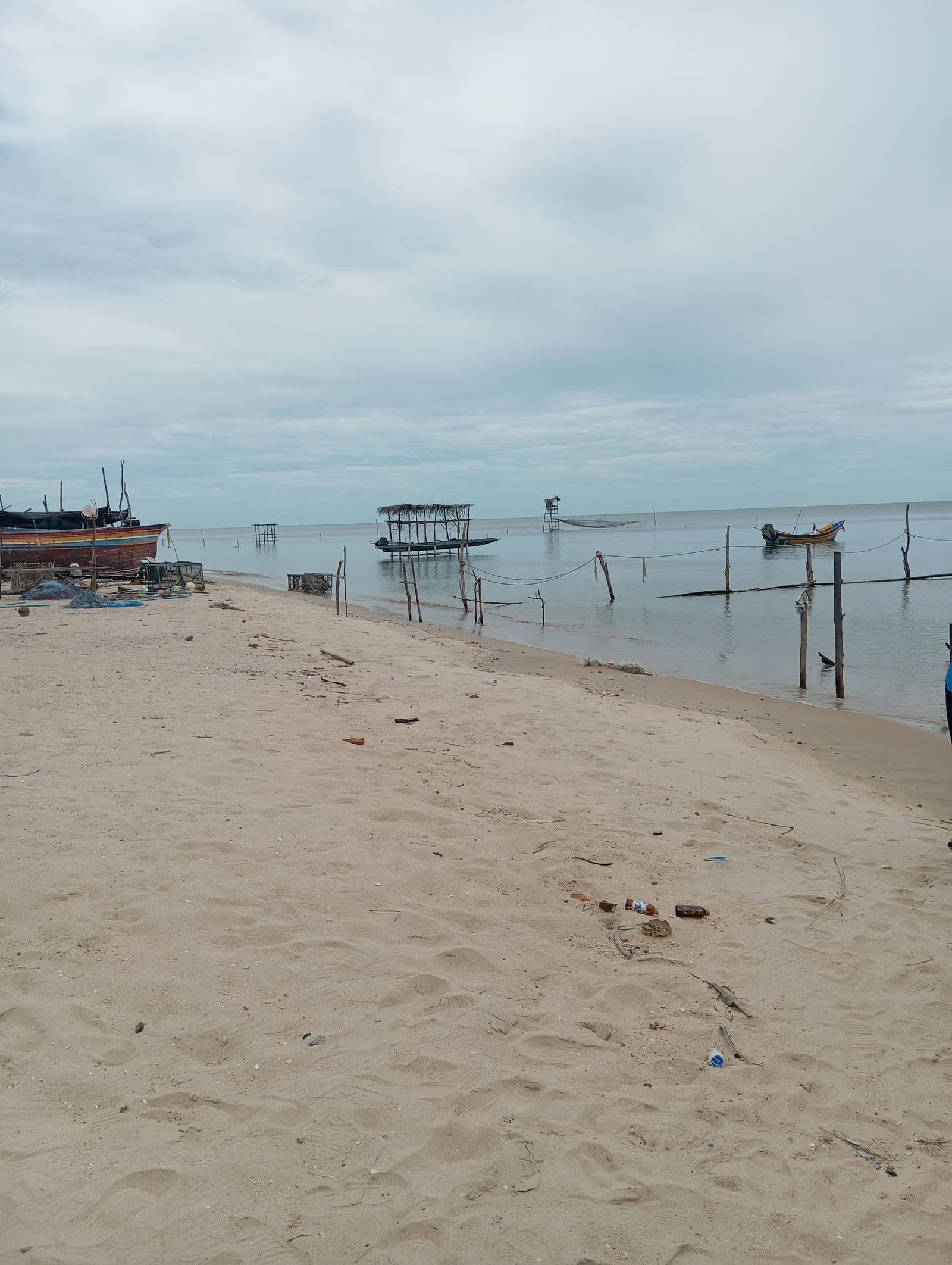 Sandy beach with turquoise waters, beachfront palm-fringed cafés, traditional boats, and Vietnamese coastal scenery on a clear sunny day