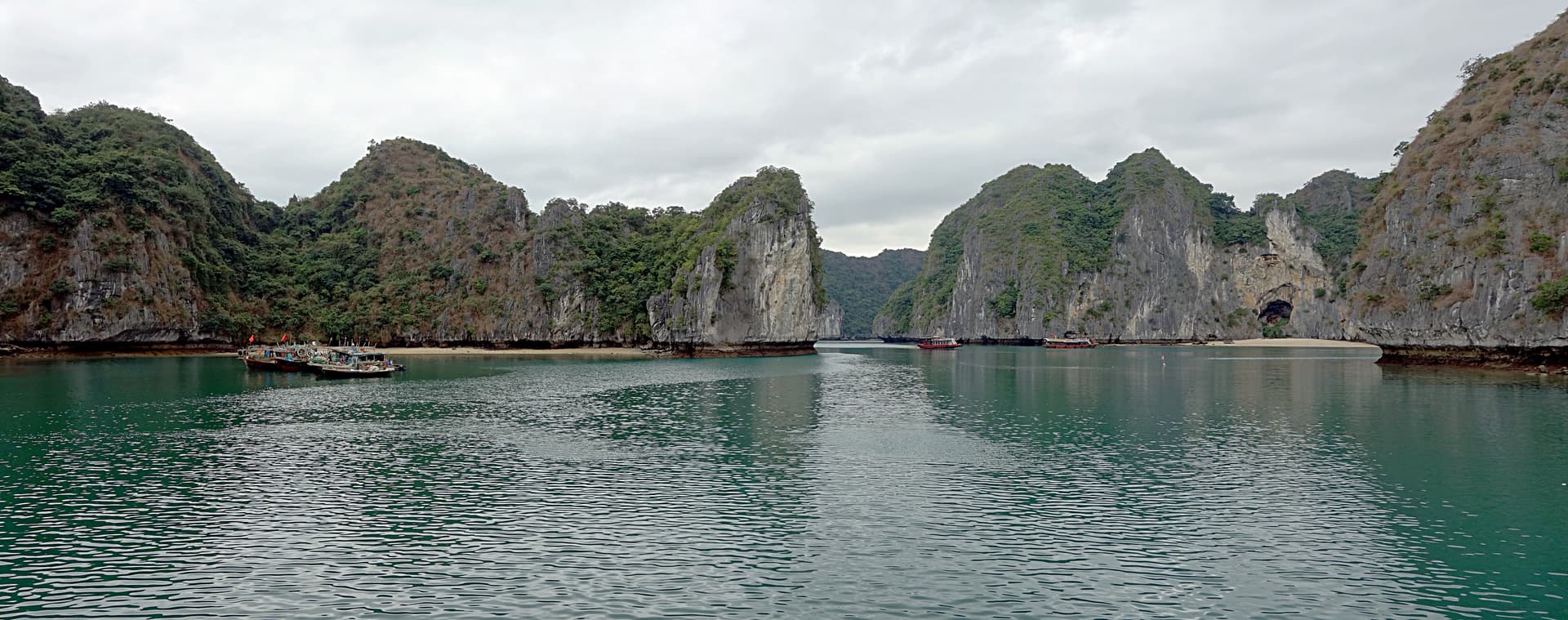 Panoramic view of Lan Ha Bay featuring limestone karst islets rising from turquoise water under clear skies