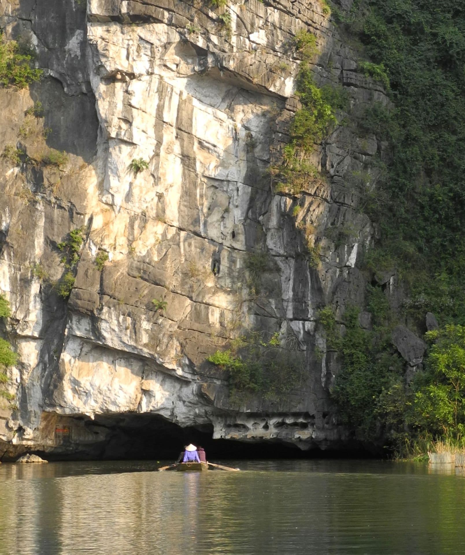 Limestone karst formations rising above a calm river in Tam Coc, Ninh Binh Province