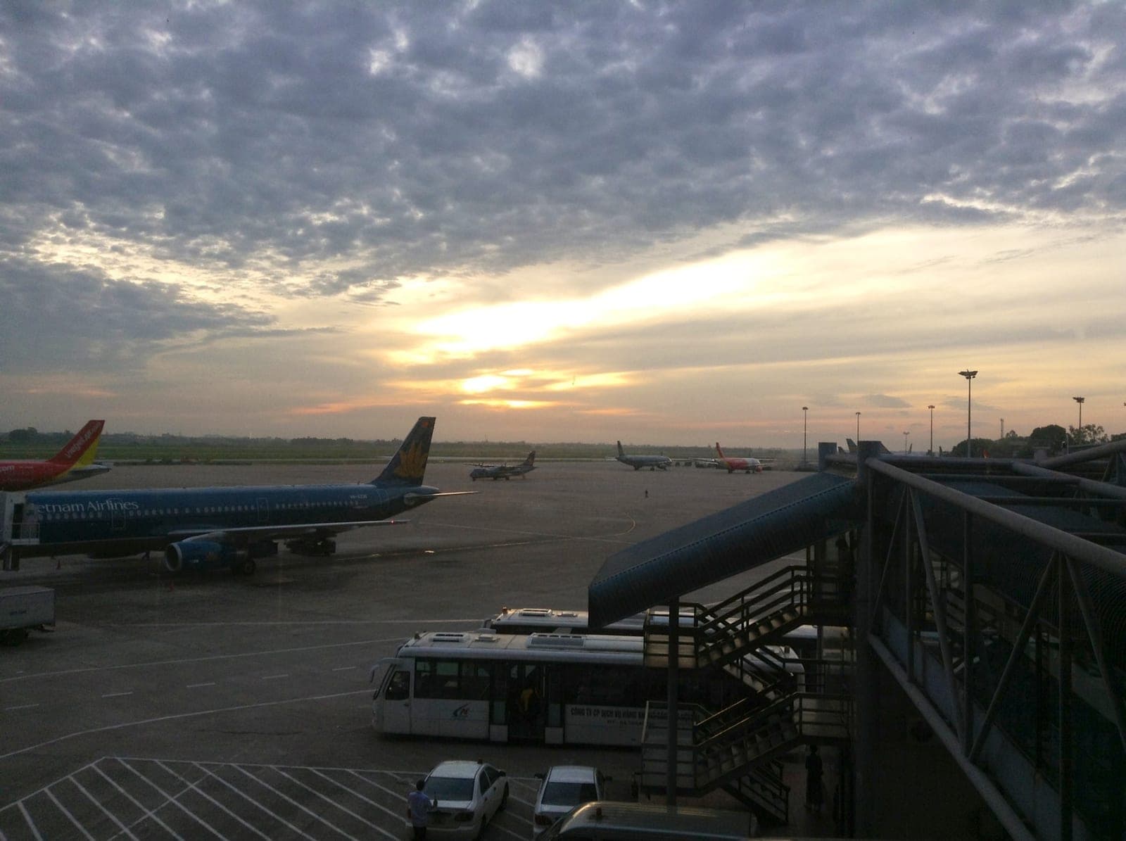 Noi Bai International Airport terminal building exterior with modern architecture, tarmac, and aircraft on a clear day.